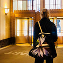 Person with a lotus flower-patterned bag entering a building with ornate entrance.