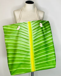 Green leaf-patterned tote bag draped over a mannequin with a white background