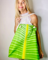 Artist Shelly Lawler  holding a green and yellow leaf tote bag against a plain background