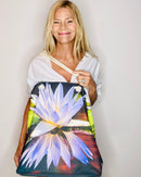 Woman holding a bag with a lotus flower design against a plain background