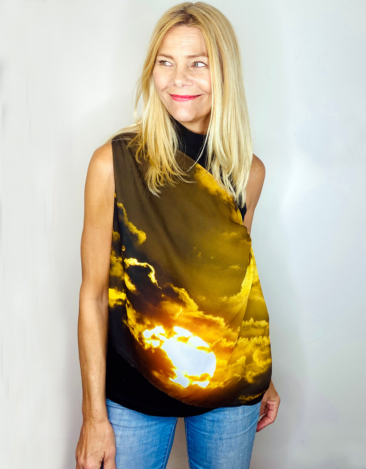 La Luna Scarf draped off one shoulder showing artwork in golden sunset tones on lightweight flowing fabric