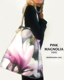 Woman holding a pink magnolia tote bag with 'shellylawler.com' text.