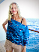 Clouds print lightweight scarf with signature pre-tied design, worn draped over one shoulder showing blue sky with white cloud pattern and flowing fabric