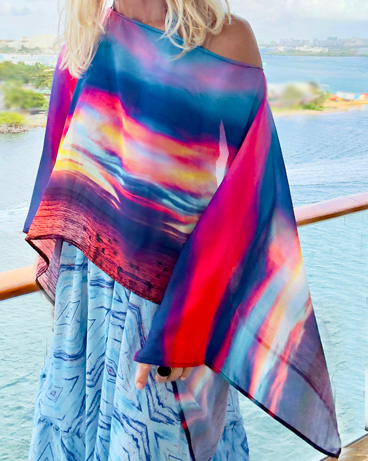 Fire in the Sky Poncho slip-over styling, closeup showing vibrant sunset artwork, lightweight flowing fabric in red, blue, orange pattern  