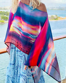 Fire in the Sky Poncho slip-over styling, closeup showing vibrant sunset artwork, lightweight flowing fabric in red, blue, orange pattern  