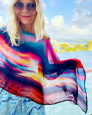 Fire in the Sky Poncho lightweight fabric flowing in wind, vibrant sunset tones, ocean background on cruise ship deck
