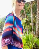 Side view of nature-inspired scarf showing sunset ocean imagery and logo detail
