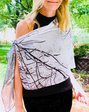 Black-and-white scarf draped across the body, showing winter branch imagery and fluid lightweight fabric