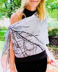 Black-and-white scarf draped across the body, showing winter branch imagery and fluid lightweight fabric