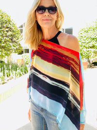 Layercake Poncho front view styled as an easy slip-over poncho, featuring bold horizontal sunset stripes and soft drape