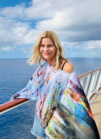 Blue Green Poncho draped over one shoulder flowing fabric in wind ocean background