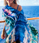 Close-up of Magic Poncho showing original artwork in turquoise with lightweight fabric flowing in the wind