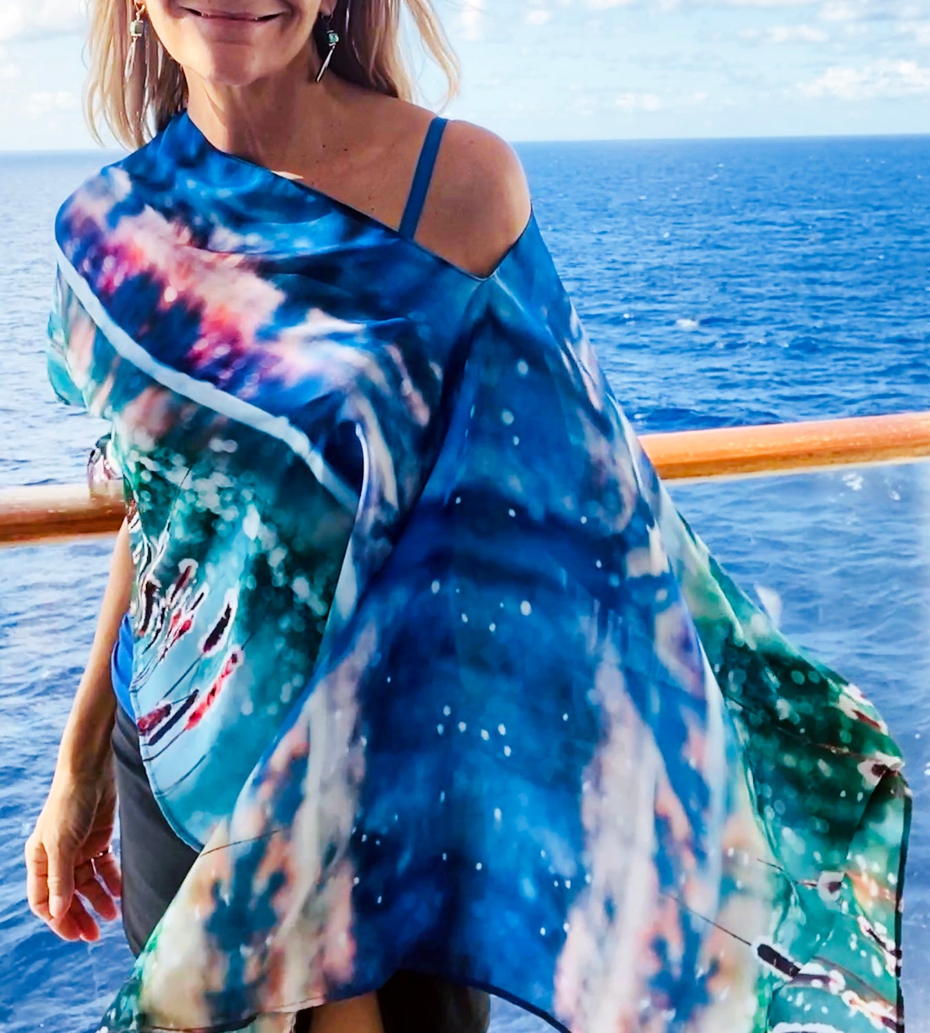 Close-up of Magic Poncho showing original artwork in turquoise with lightweight fabric flowing in the wind