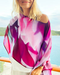 Close-up of Royal Poncho showing abstract floral artwork in purple, pink, white, and red with lightweight flowing fabric texture