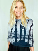 Black-and-white coastal print scarf featuring water and trees draped in a boatneck style with lightweight fluid movement