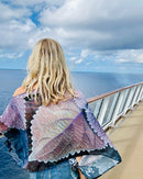 Back view of Coleus Poncho showcasing original leaf artwork in purple and blue with lightweight fabric flowing in the wind