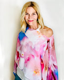 Cherry Blossom Poncho with slip-over design, draped over one shoulder showing original floral artwork in pink, white, and blue with lightweight fabric drape