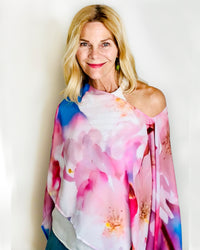 Cherry Blossom Poncho with slip-over design, draped over one shoulder showing original floral artwork in pink, white, and blue with lightweight fabric drape