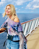 Coleus Poncho with slip-over design, lightweight fabric draped off one shoulder showing original leaf artwork in purple and blue tones against an ocean backdrop