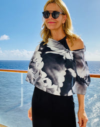 IInfrared Scarf with signature pre-tied design, worn off one shoulder showing abstract floral forms against an ocean backdrop