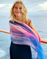 Transatlantic Poncho styled over shoulder, highlighting cool sunset tones in blue and pink with flowing movement